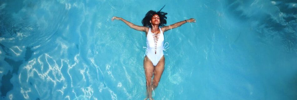 woman in white monokini swimming on body of water